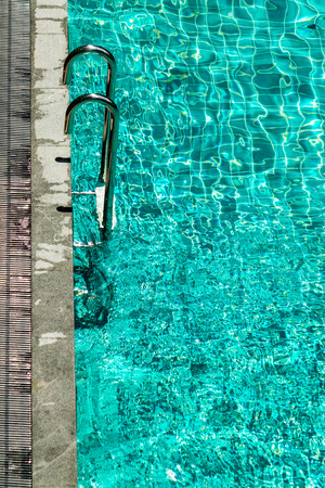 Swimming pool with stairs and water ripple with light reflextion.の写真素材