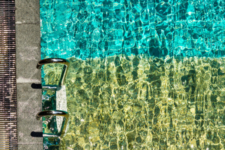 Swimming pool with stairs and water ripple with light reflextion.の写真素材