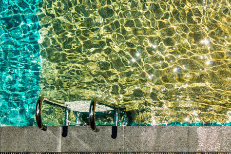 Swimming pool with stairs and water ripple with light reflextion.の写真素材