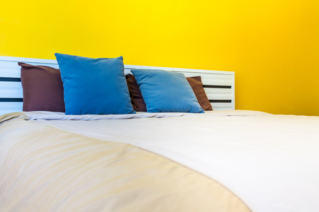 Ready for bed, White bed linens and refreshing colorful wallpaper in simple bedroom.の写真素材