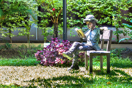 Alloy Children reading book on chair in home garden.の写真素材