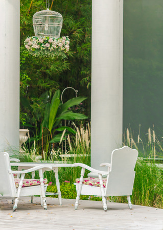 White table set and flower pot on relaxing space in cozy garden on summer.の写真素材