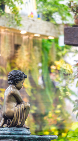 Statue Cupid and waterfall in cozy garden on summer.の写真素材