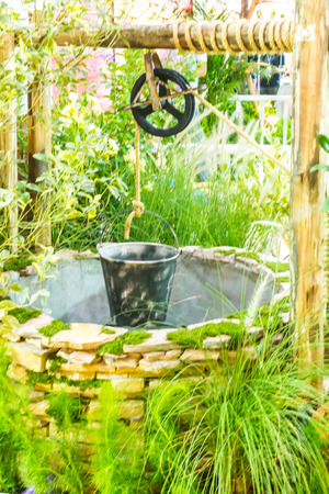 Artesian well and bucket in cozy garden.の写真素材