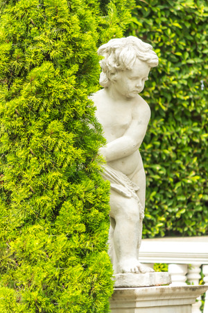Statue of Cupid in cozy garden on summer.の写真素材
