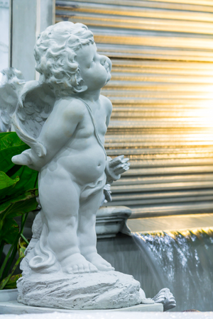 Statue Cupid and waterfall in cozy garden.の写真素材