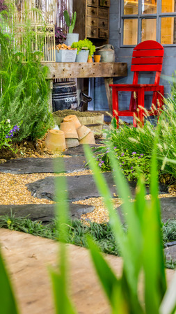 Relaxing area with red chair in cozy garden.の写真素材