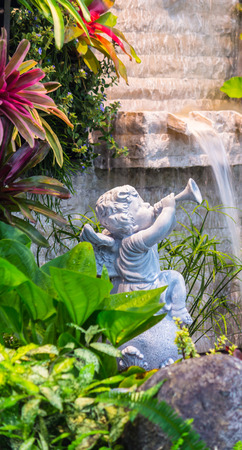 Statue Cupid and waterfall in cozy garden.の写真素材