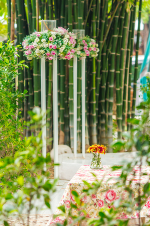 White table and flower vase on relaxing space bamboos background in cozy garden on summer.の写真素材