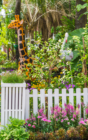 White picket fence surrounded by flowers in  front garden on summer.の写真素材