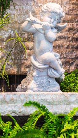 Statue Cupid and waterfall in cozy garden.の写真素材