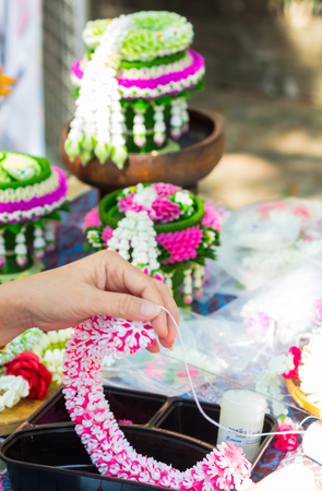 Thai woman making a tradition Thai flowers garland activities in Songkran festival, Bangkok Thailand.の写真素材