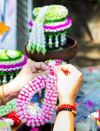Thai woman making a tradition Thai flowers garland activities in Songkran festival, Bangkok Thailand.の写真素材