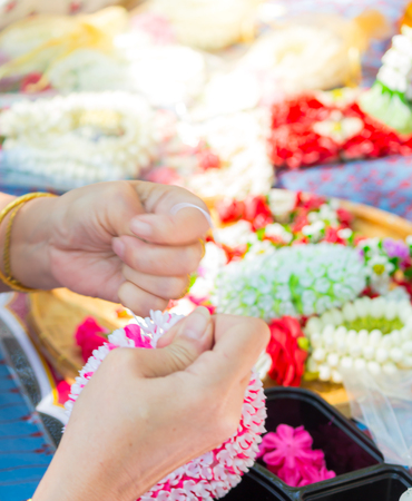 Thai woman making a tradition Thai flowers garland activities in Songkran festival, Bangkok Thailand.の写真素材