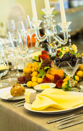 Party dinner table setting with tableware and silverware and glasses set and Candlestick and flower...