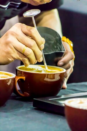 Showcase Barista making Latte art coffee and Barista pouring fresh milk create art pattern on Latte coffe.の写真素材