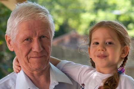 Grandfather is holding smiling granddaughter. The older man isnÕt clean-shaven. DonÕt be too harsh to him Ð he just came from night shift and had no time to shave.の写真素材