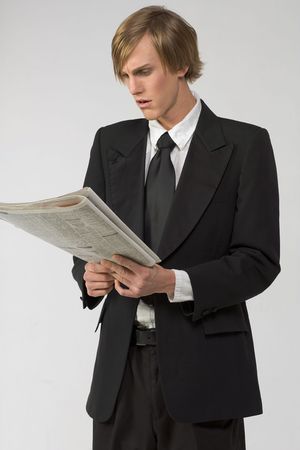 Businessman reading newspaper and apparently shocked by the contentの写真素材