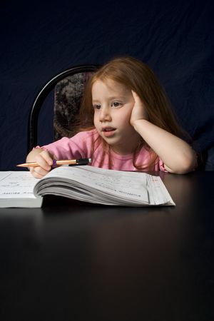 Redheaded girl with book by the black tableの写真素材