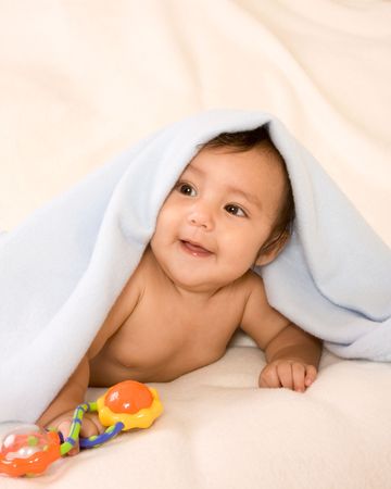 cute kid lying down on his tummy on blanket with stuck out tongue playing peek-a-booの写真素材