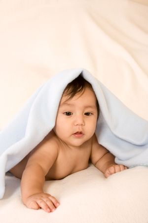 cute kid lying down on his tummy on blanket playing peek-a-booの写真素材