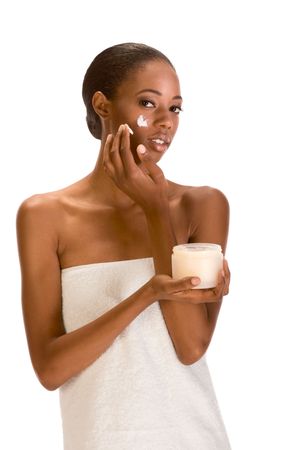 Beautiful young ethnic woman with Slicked Back Hair wrapped in white bath towel applying moisturizer on her face の写真素材