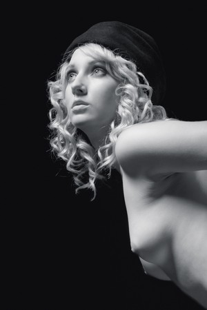 Nude beautiful blond with curly hair and developed firm breast wearing hat, standing and bending forwardの写真素材