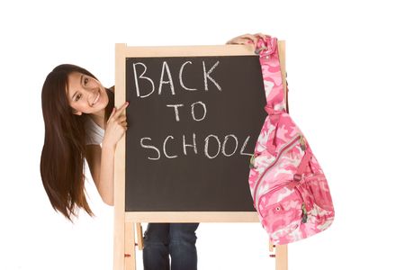 Friendly young ethnic High school girl student of mixed Vietnamese and Chinese race standing by chalkboard with hanging backpack and pointing to the text - back to schoolの写真素材