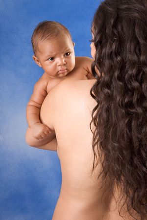 naked Hispanic mom holding her biracial mix of Hispanic and African American baby son against blue backgroundの写真素材