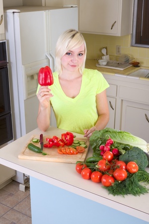 Caucasian female presenting bell peppers holding in hands by kitchen countertopの写真素材