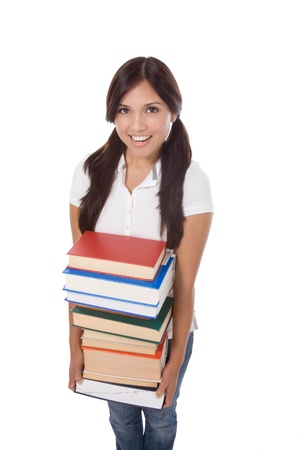 Young Hispanic female college student in jeans holding huge pile of educational books from libraryの写真素材