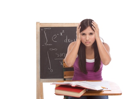 Stressed High school or college Latina female student sitting by the desk at math class. Blackboard with complicated advanced mathematical formals is visible in backgroundの写真素材