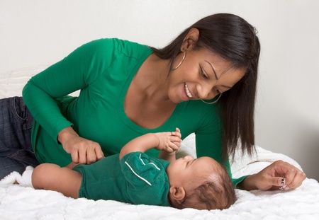 Biracial mom on bed with her multiethnic black infant son (baby is 3 months old)の写真素材