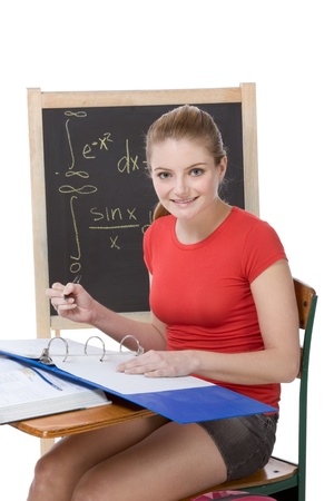 High school or college female student sitting by the desk at math class. Blackboard with advanced mathematical formals is visible in backgroundの写真素材