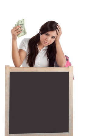 Ethnic Hispanic college student with notebook and backpack holds pile 100 (one hundred) dollar bills happy getting money frustrated by exuberant raising tuition cost and unaffordable education forcing into debtの写真素材