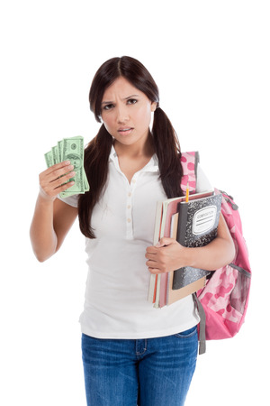 Ethnic Hispanic college student with notebook and backpack holds pile 100 (one hundred) dollar bills happy getting money frustrated by exuberant raising tuition cost and unaffordable education forcing into debtの写真素材