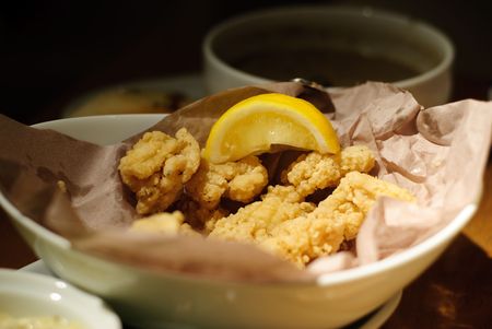 Dish of fried calamari rings in dimly lit restaurantの写真素材