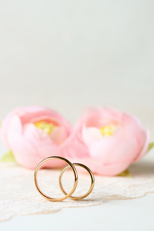 Delicate background with wedding rings and flowers.の写真素材