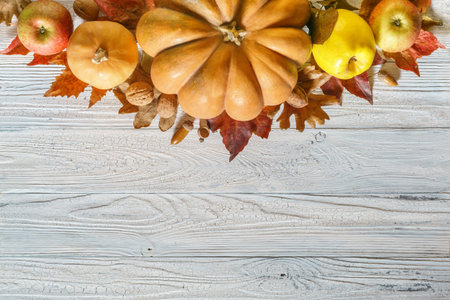 Autumnal decor from pumpkins, apples and leaves on a white rustic wooden background. Flat lay autumn...