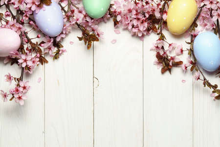 Eeaster background with cherry blossom and easter eggs on wooden table. Space for text.の写真素材