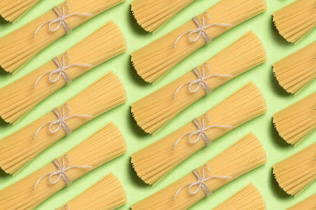 Pattern with spaghetti on a green paper background. Raw Italian paste. Yellow long spaghetti. Raw spaghetti. Food concept.の写真素材