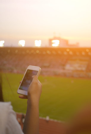 Women are using smart phone on the soccer stadium.の写真素材