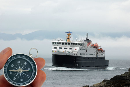 Hand holding a compass in front of a ferry