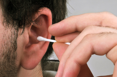 Man cleaning his ears with a cotton swabの写真素材