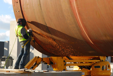 Worker grinding a steel cylinder