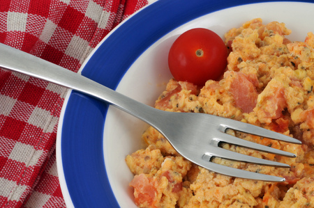 Plate of scrambled eggs with a cherry tomatoの写真素材