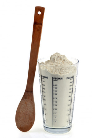 Flour cup of flour and wooden spoon on white backgroundの写真素材
