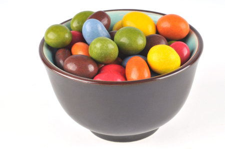 Bowl of peanuts coated with chocolate on a white background