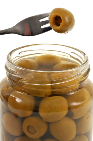 A quilted olive with a fork over a jar of olivesの写真素材