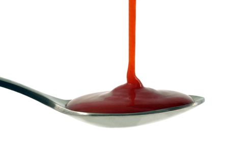 Ketchup spoon in closeup on white backgroundの写真素材